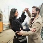 Un couple souriant en train de danser sur un quai de gare.