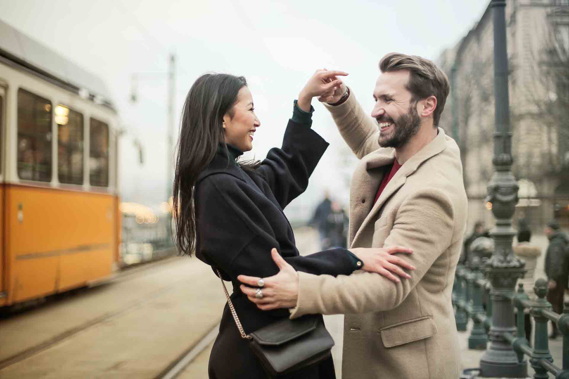 Un couple souriant en train de danser sur un quai de gare.